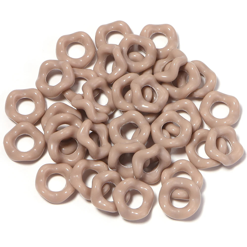 A pile of light beige acrylic doughnut spacer beads for jewelry making