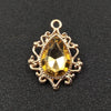 Gold plated water droplet charm featuring a faceted yellow crystal and an ornate flower design.