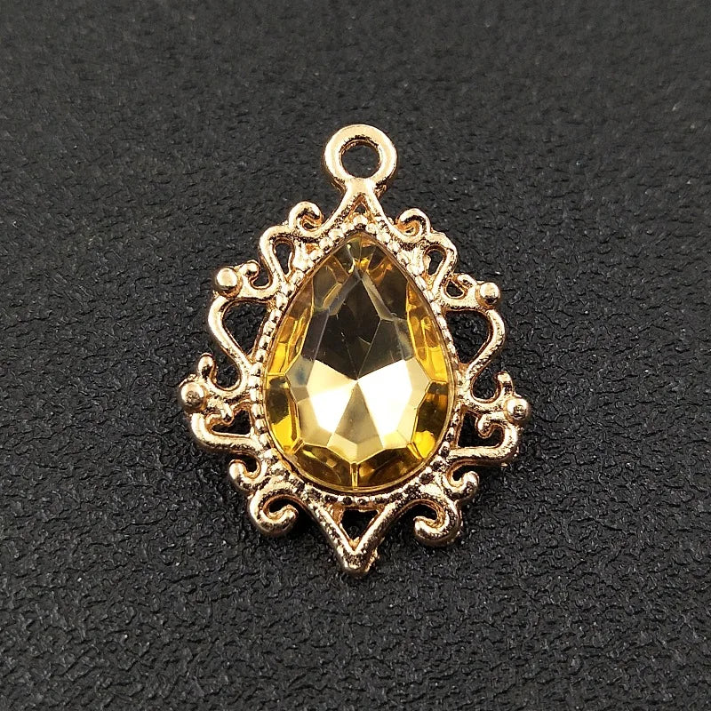 Gold plated water droplet charm featuring a faceted yellow crystal and an ornate flower design.