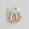 A beige baby girl sleeveless jumpsuit with a white lace collar and gathered fabric details.