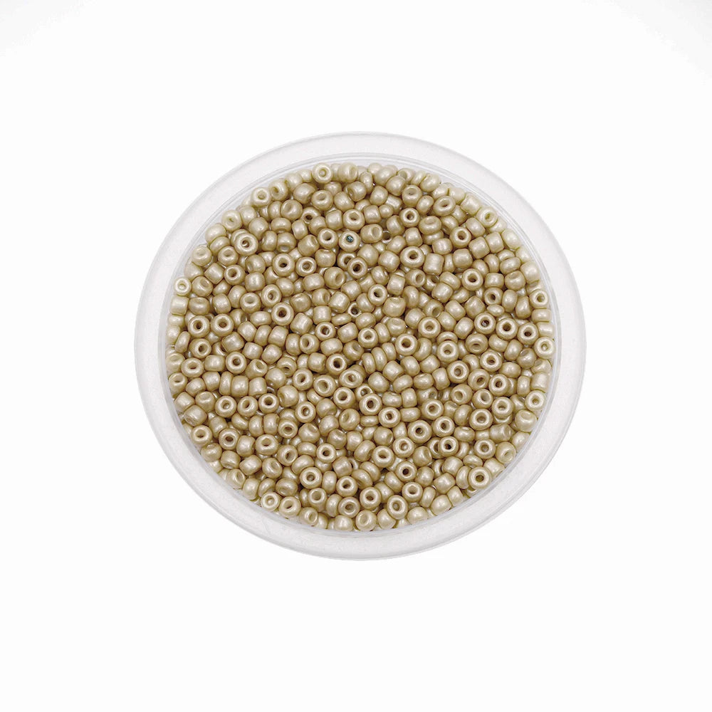 A clear plastic container filled with small, round, light beige glass seed beads for jewelry making.