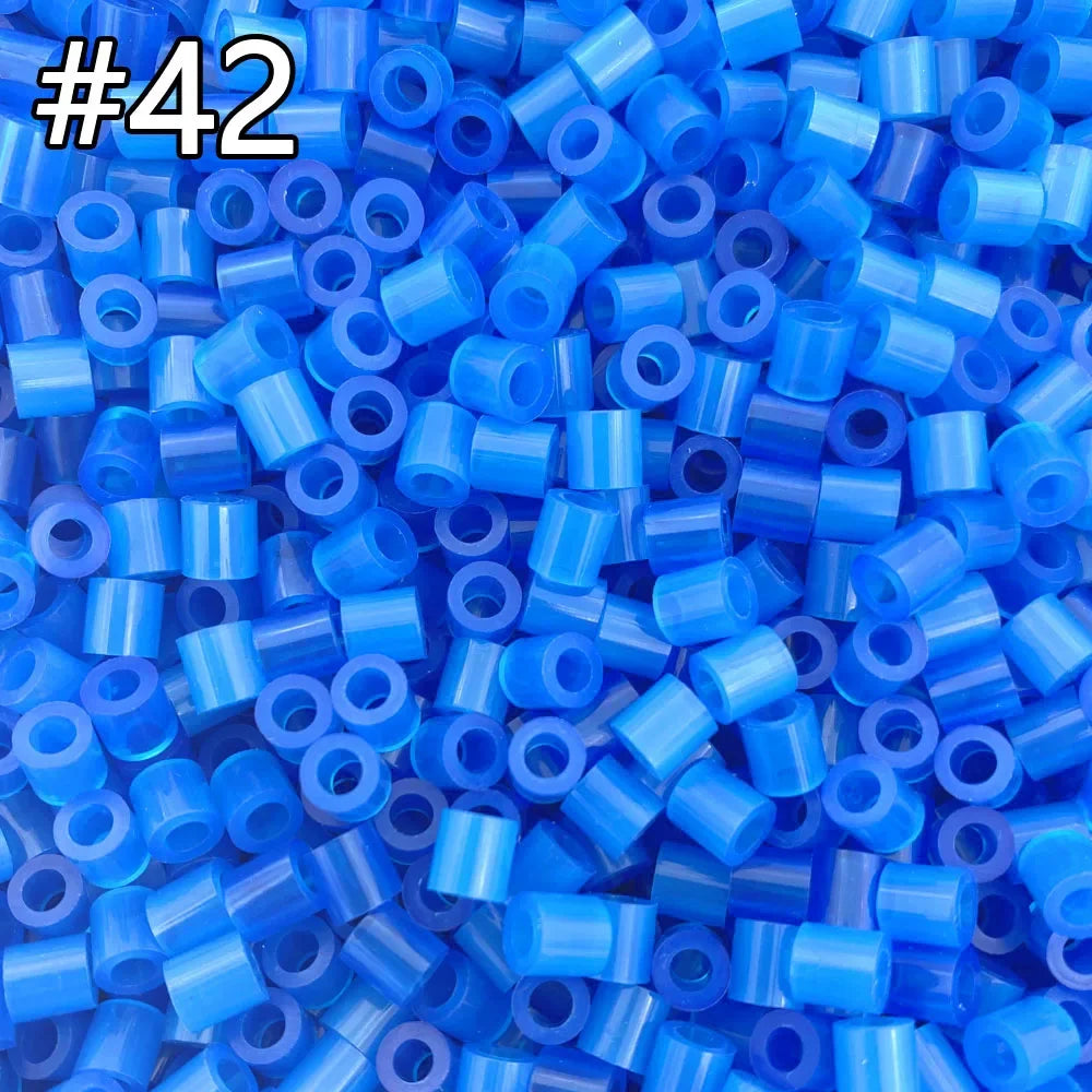 A close-up view of many small, assorted blue and purple plastic fuse beads for crafting projects.