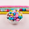 A bowl filled with colorful silicone lentil beads in various shades of pink, blue, yellow, and green.