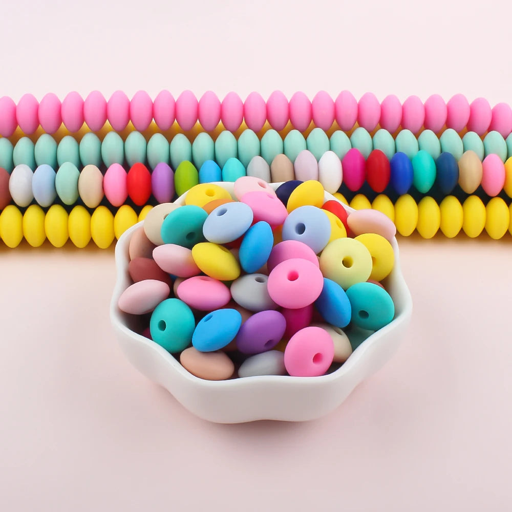 A bowl filled with colorful silicone lentil beads in various shades of pink, blue, yellow, and green.