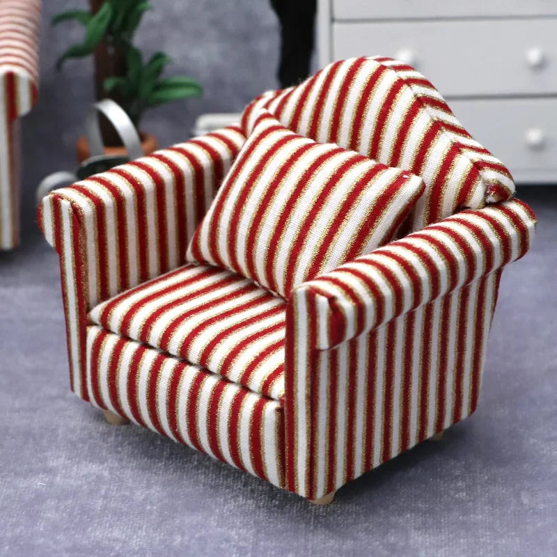 A miniature red and white striped sofa and pillow set for a dollhouse