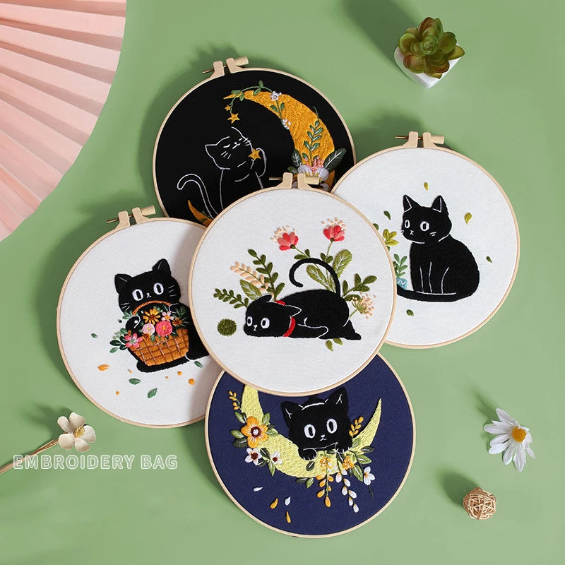 A collection of embroidery kits featuring black cats and floral designs on white and dark backgrounds.