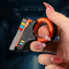 A hand holds an orange and black magnetic fidget push card with a spinner for stress relief.