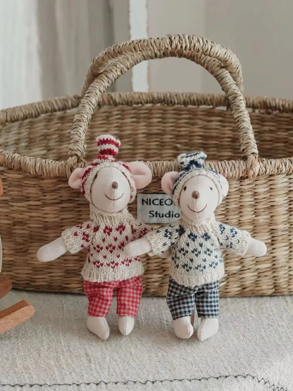 Two handmade mouse plush dolls wearing retro knitted outfits standing in front of a woven basket