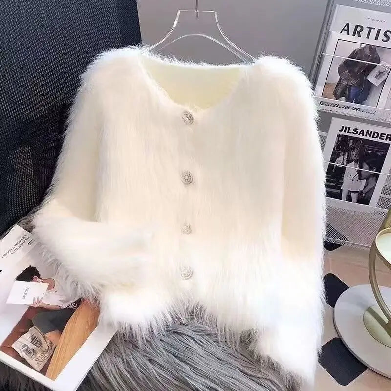 A white faux fur cardigan sweater draped on a hanger against a dark background.