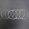 A collection of silver-plated classical guitar strings with transparent nylon cores arranged in a line.