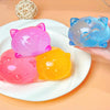 Three silicone cat squishy toys in pink, yellow, and blue are displayed on a white plate.