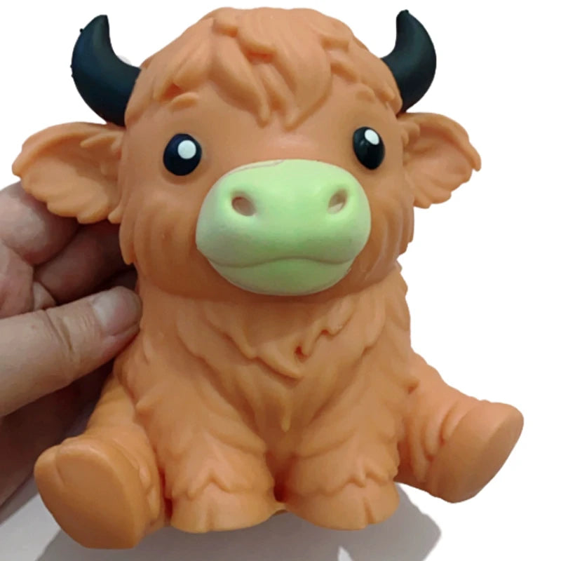 An orange squishy stress ball shaped like a Highland cow with black horns and large eyes.