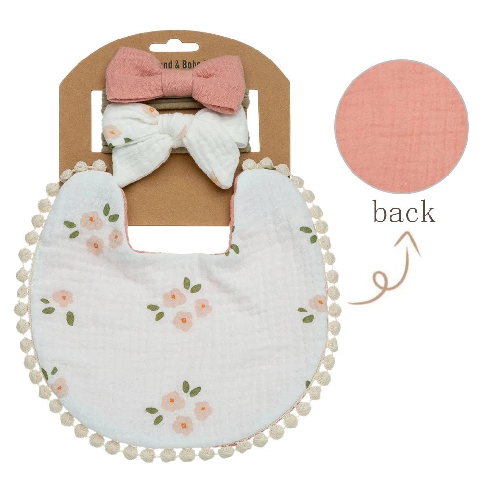 A baby flower bib and headband set featuring a pink bow and a white floral-patterned bib.