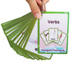 A hand holds a stack of green flashcards featuring verbs like dance and other action words.