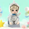 A small, fluffy gray doll with a hood and blue bowtie is seated in a striped chair.