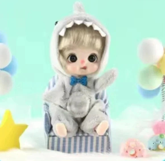 A small, fluffy gray doll with a hood and blue bowtie is seated in a striped chair.