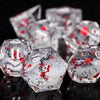A close-up of a set of clear resin dice with red plum blossom designs, reflecting on a dark surface.