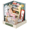 A wooden miniature dollhouse kit featuring a pink and white aesthetic with decorative elements like lace and gold accents.