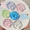 A collection of pink, blue, and green crystal cat claw squishy toys on a white plate.