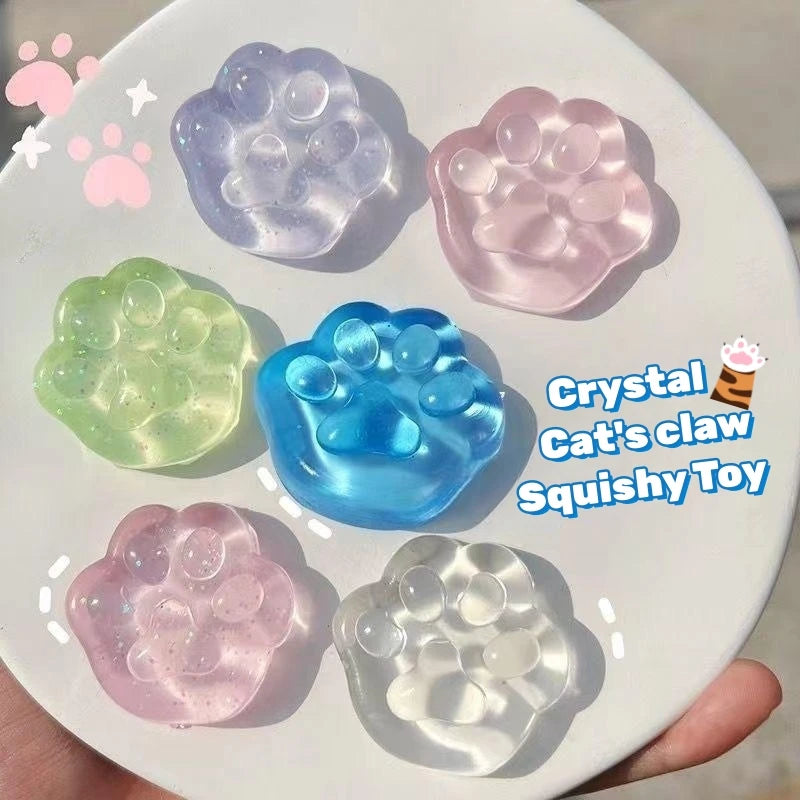 A collection of pink, blue, and green crystal cat claw squishy toys on a white plate.