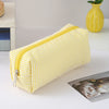 A yellow and white striped canvas pencil case with a zipper is shown on a white surface.
