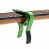 A green aluminum alloy quick-change guitar capo clamped onto a wooden guitar neck.