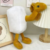A yellow shark plush toy with a white body is displayed next to a framed sign.
