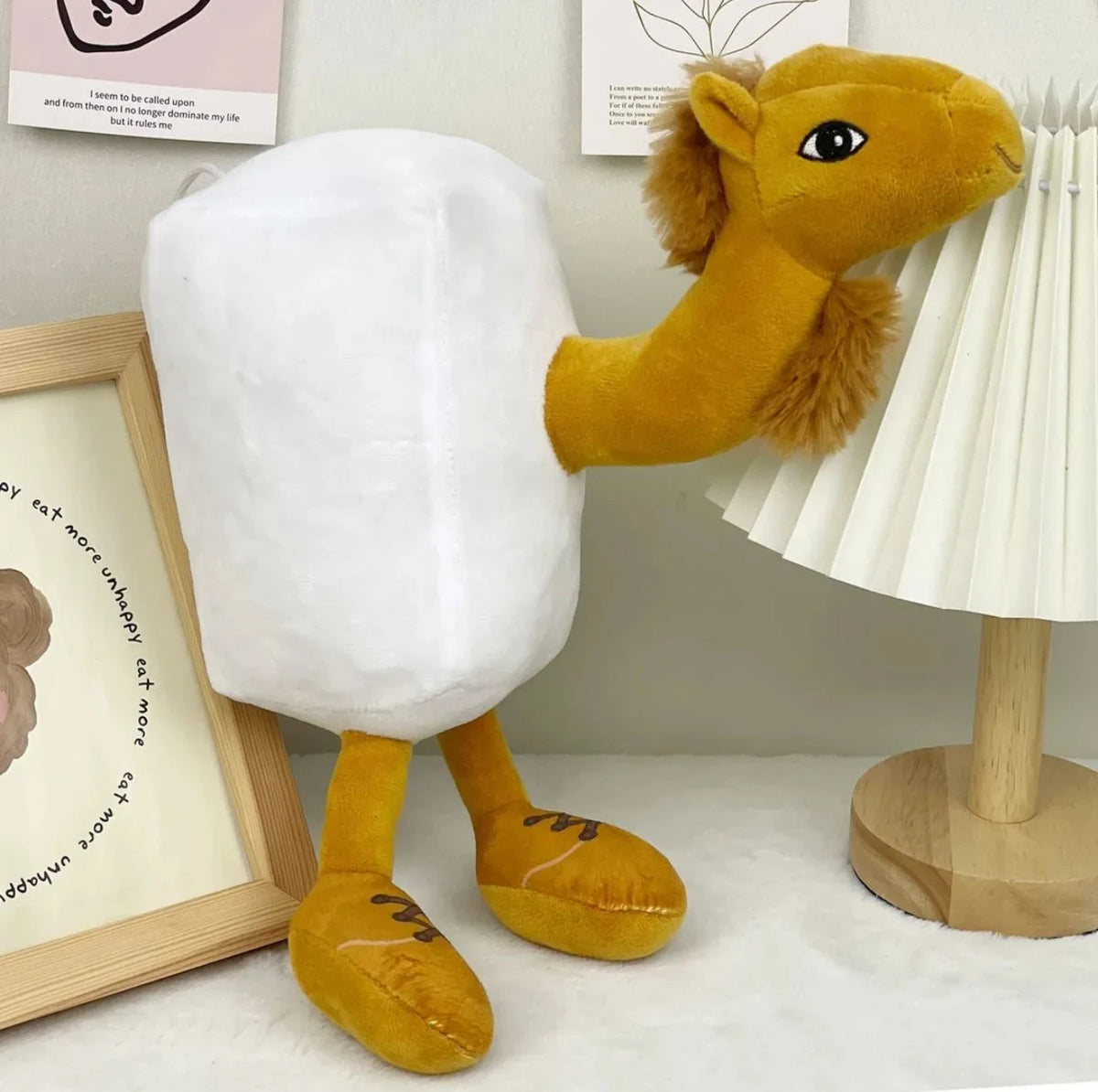 A yellow shark plush toy with a white body is displayed next to a framed sign.