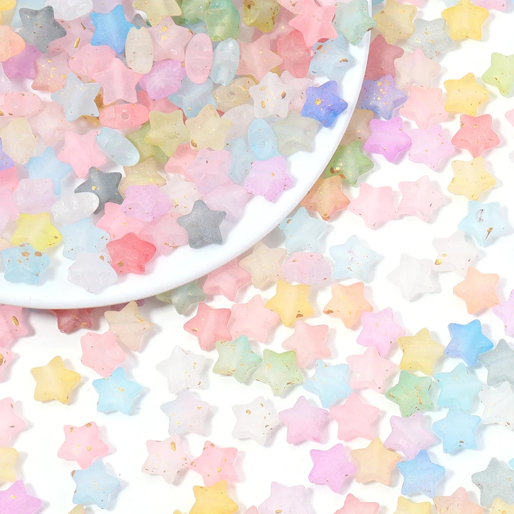 A scattered collection of colorful transparent star acrylic beads in pastel shades across a white surface.