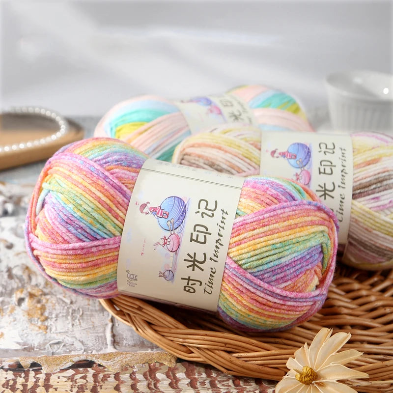 A stack of three skeins of gradient acrylic yarn in pink, purple, and green hues for knitting and crochet.