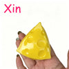 A hand is holding a yellow, triangular cheese ball stress relief squeeze toy.