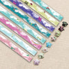 A collection of 27 assorted colored origami star strips laid diagonally on a light background.