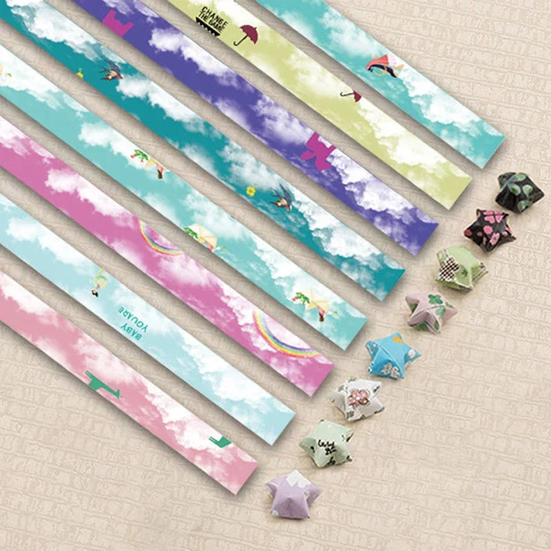 A collection of 27 assorted colored origami star strips laid diagonally on a light background.