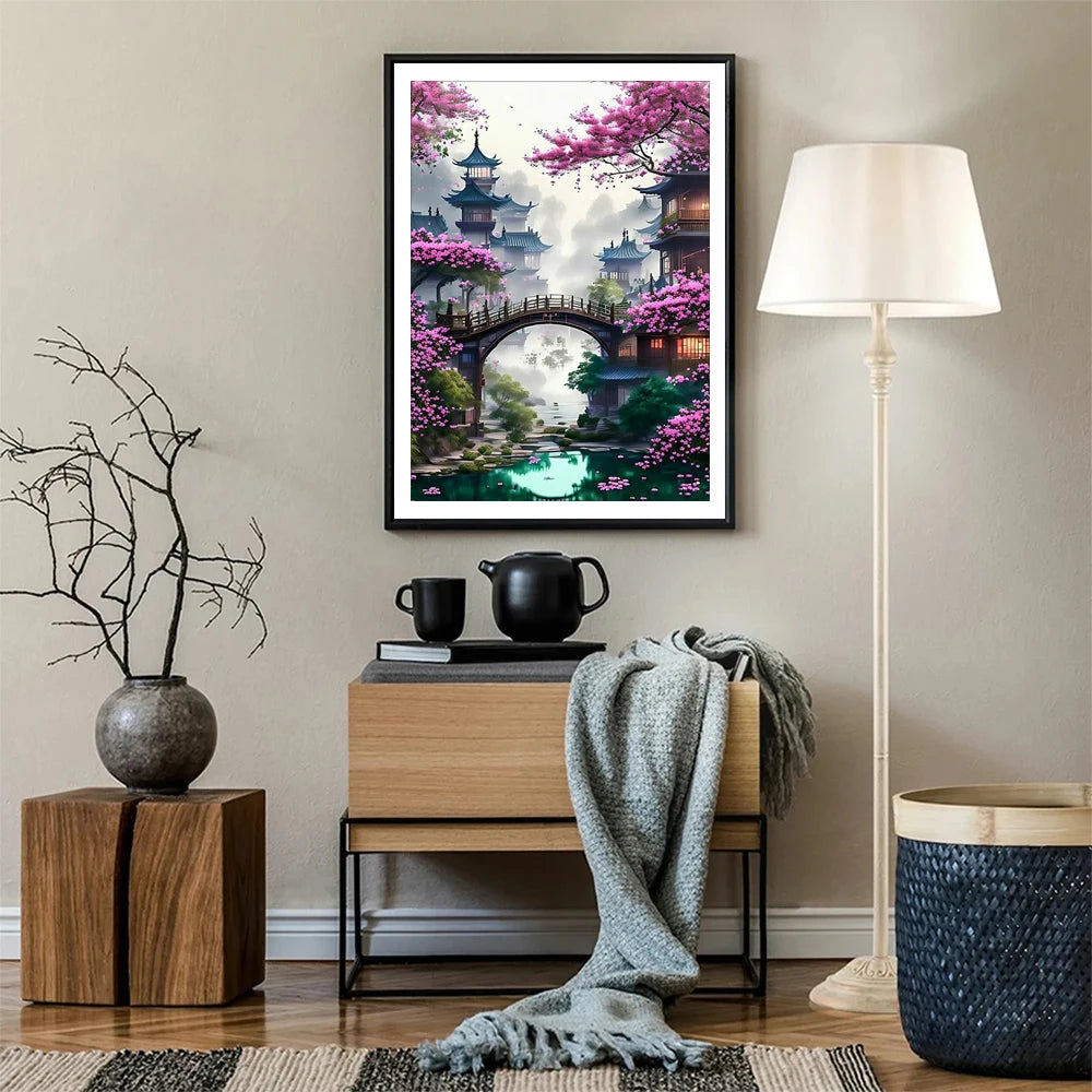 A framed painting depicting a scenic cityscape with pink cherry blossoms and an arched bridge.
