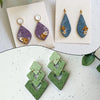 Pair of teal and purple teardrop clay texture rollers with gold ear wires and small floral accents