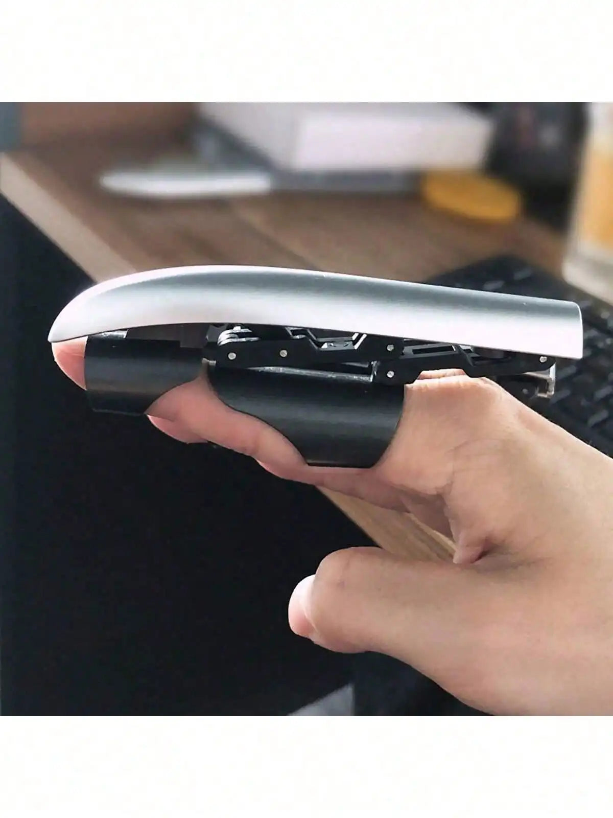 A hand holds a silver retractable mechanical wolf claw prop with black grips and flexible knuckles.