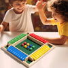 Two children play a wooden shut the box dice game with colored dice on a green board.