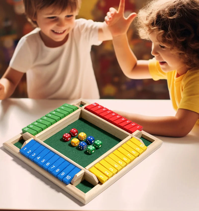 Two children play a wooden shut the box dice game with colored dice on a green board.