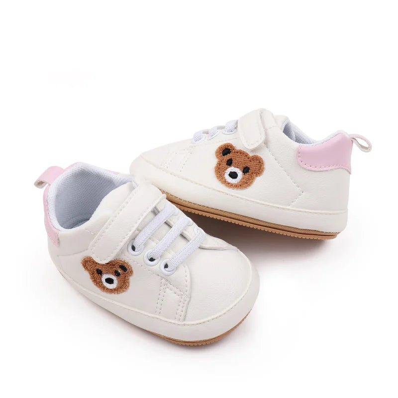 A pair of white and pink bear-themed baby sneakers for first walkers.