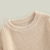 A close-up of a light beige knit pullover sweater with a ribbed neckline and textured body.