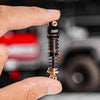 A hand holds a black heavy-duty oil shock absorber for an RC crawler.