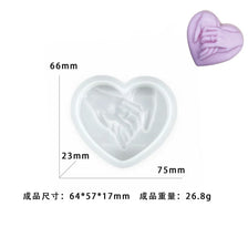 A pink heart-shaped silicone mold with a detailed hand design, shown in various views.