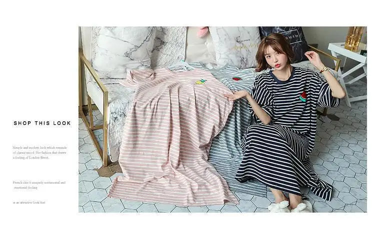 A woman models a pink and white striped short-sleeve lounge dress in a studio setting.