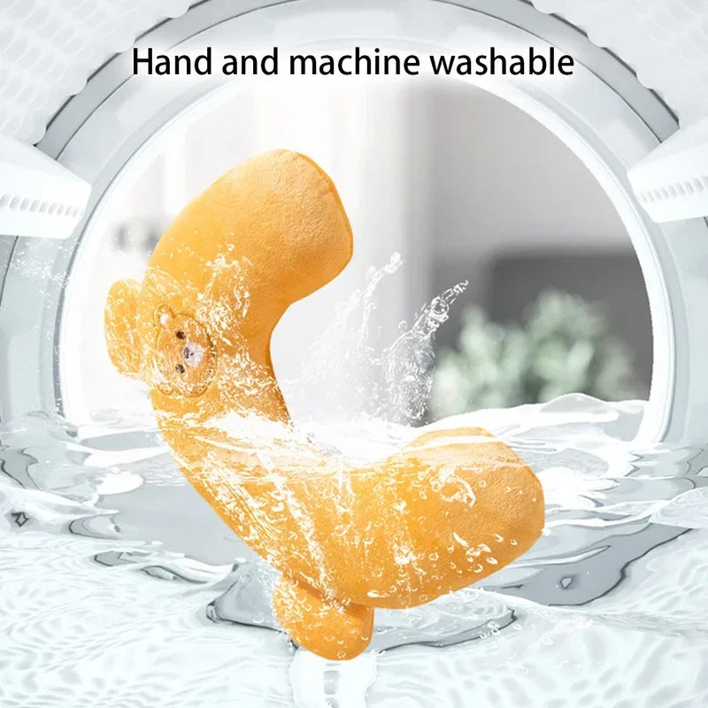 A yellow plush U-shaped pet pillow being washed under running water.