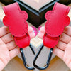 A pair of red PU leather stroller organizer hooks with black clasps are shown being held in a hand.