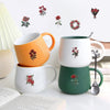 A set of ceramic mugs in white and orange colors with red rose designs displayed on a white surface.