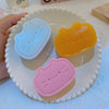 Three squishy toys shaped like cats and cheese in blue, orange, and pink resting on a white plate.
