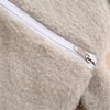 Close-up of a light beige plush-covered hot water bottle with a silver zipper detail.