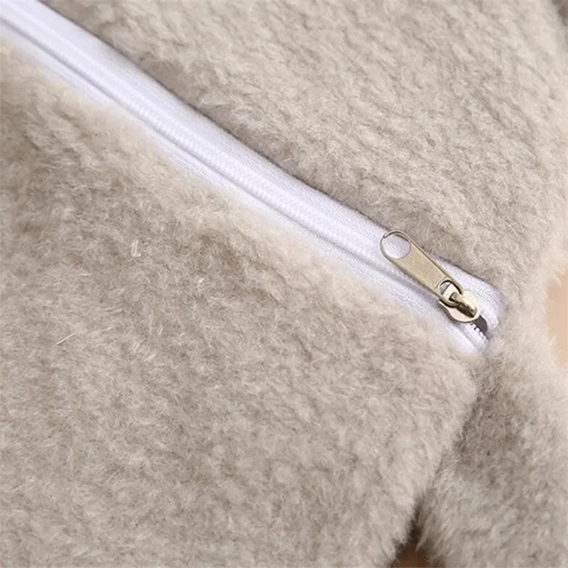 Close-up of a light beige plush-covered hot water bottle with a silver zipper detail.