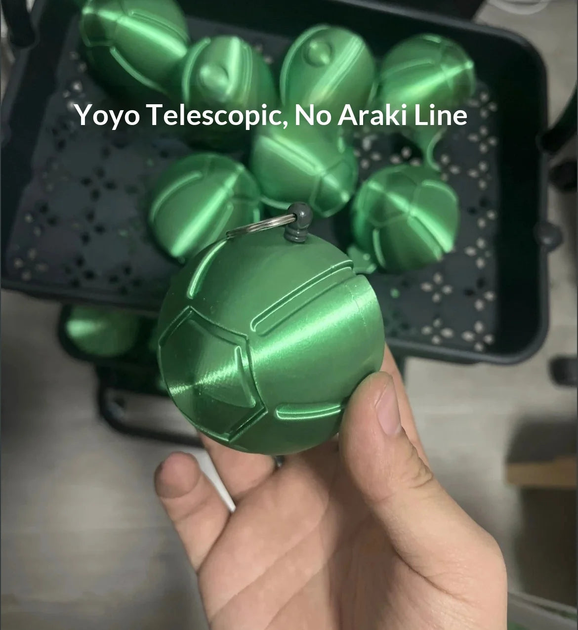 A hand holds a green Yoyo Telescopic No Araki Line fidget toy, which is a steel ball run stress relief toy.